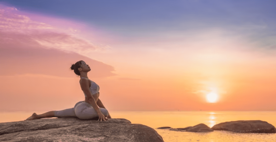 Mulher jovem praticando Yoga ao ar livre nas pedras em frente a praia