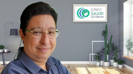 Roger, hipnoterapeuta, homem de pele clara, cabelos curtos e escuros, com óculos pequenos, um leve sorriso e camisa azul.