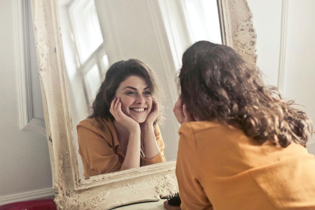 Mulher sorrindo de bem com a vida e consigo mesma.