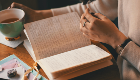 Pessoa escrevendo em um diário com chá e cristais ao lado, representando sinais do despertar espiritual